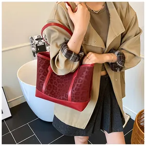 Detail of red leopard print tote bag with leather straps in a lifestyle setting