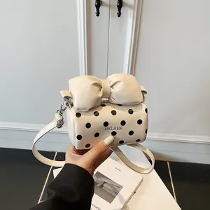 Chic mini polka dot barrel bag in creamy white with a large bow and shoulder strap