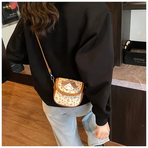 Detail of floral crossbody bag with a cute 3D puppy plush and brown leather strap