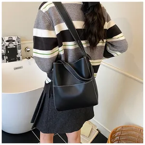 Detail of black leather bucket bag with white contrast stitching and wide shoulder strap