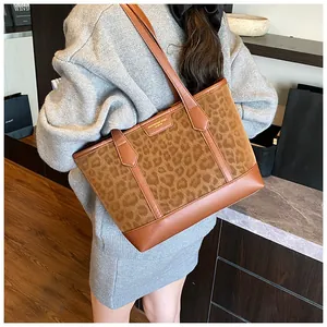 Detail of leopard print tote bag with brown faux leather trim and gold logo plaque