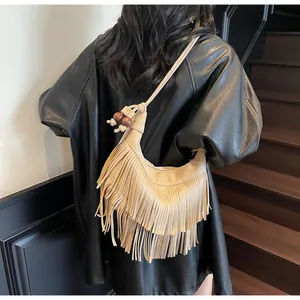 Detail van boheemse suède crossbody tas met lange franjes en decoratieve houten kralen