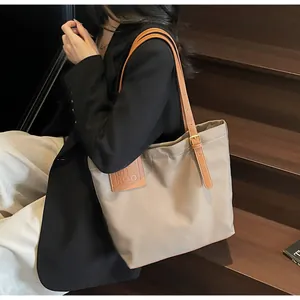 Detail van verstelbare bruine leren riemen en MIROO-logo in reliëf op beige tote bag