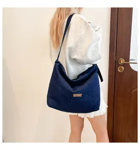 Dettaglio di una grande borsa tote in denim con etichetta in pelle su tessuto blu scuro