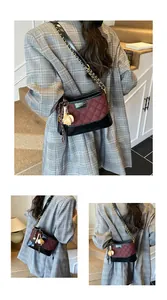 Detail view of burgundy quilted fabric and black leather bucket bag with chain strap