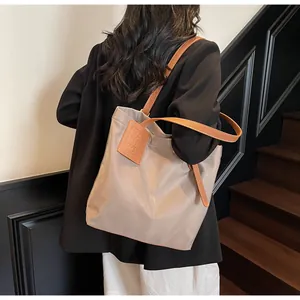 Groot taupe nylon tote tas detail met bruine lederen handgrepen en contrast stiksel
