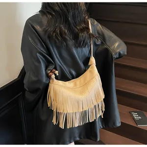 Detail van beige imitatie suède crossbodytas met lange franjes en houten kraalaccenten