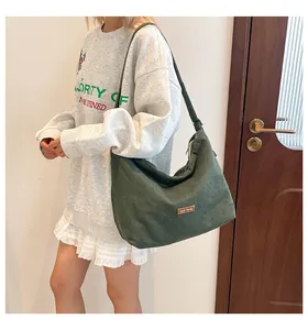 Dettaglio borsa hobo verde scuro con logo in metallo marrone e tracolla larga morbida