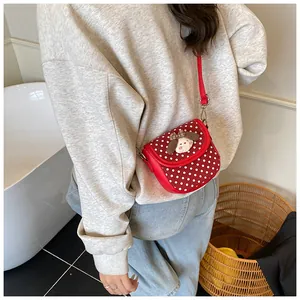 Detail of a red polka dot crossbody bag with a 3D cartoon puppy doll on the flap
