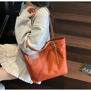 Detail van de oranje nylon draagtas met leren handvatten en ROO-logo in reliëf