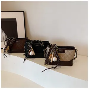 Close-up of quilted bucket bags in brown, black, and beige with baseball charms