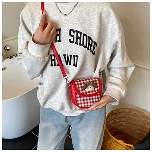 Detail of red checkered crossbody bag with cute plush puppy and red shoulder strap