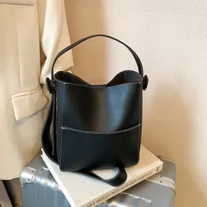 Minimalist black bucket bag with white contrast stitching and versatile shoulder straps