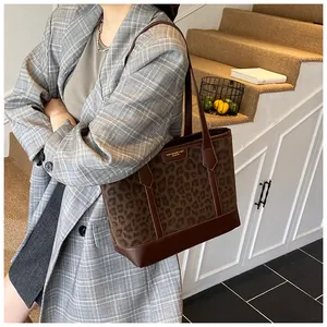 Close-up of leopard print tote bag with brown leather trim and golden logo detail