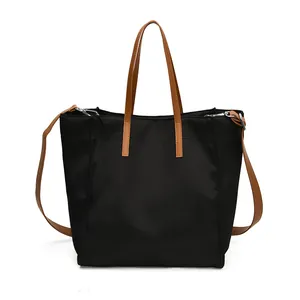 Large black nylon tote bag with brown leather handles and a detachable shoulder strap