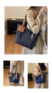 Detail van donkerblauwe nylon tote bag met bruine leren riemen en logo-patch