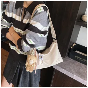 Détail du sac messager beige avec broderie cœur et charmant pendentif en forme d'ours