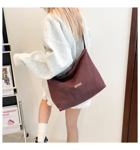 Dettaglio della borsa tote in velluto bordeaux con toppa in pelle e grande capienza