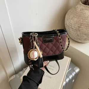 Quilted burgundy bucket bag with chain strap, baseball pendant, and elegant travel vibe
