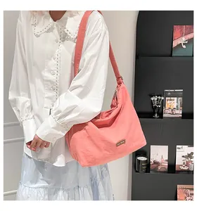 Dettaglio borsa hobo in tela rosa con tracolla larga e targhetta in metallo our fave