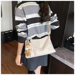 Détail du sac messager crème avec imprimé CHU DON et breloque ours mignon sur la bandoulière