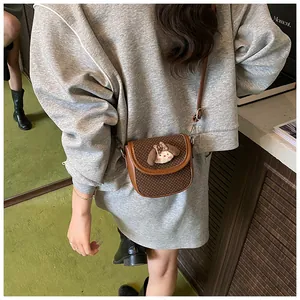 Detail of a brown polka dot crossbody bag with cute plush animal decor on model