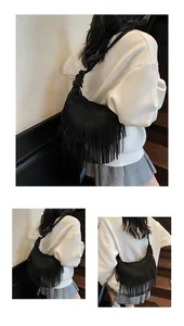Detailweergave van zwarte suède schoudertas met lange bohemian franjes en knoopdetails