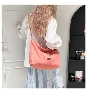 Borsa tote in tela rosa corallo indossata da una modella per mostrare capacità e design