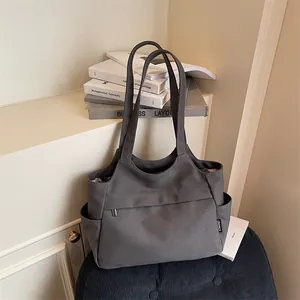 Grand sac cabas en toile gris foncé avec poches latérales sur un tabouret bleu