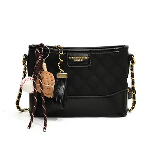 Retro black quilted bucket bag with gold chain strap and sports themed charms on white background