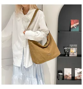 Dettaglio della grande borsa tote in denim marrone con etichetta e tracolla larga
