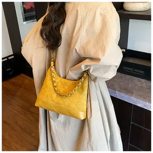 Détail du sac à bandoulière en daim jaune matelassé avec chaîne dorée et fermoir