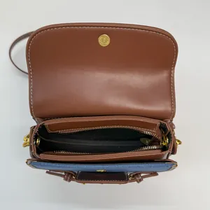 Borsa a sella in pelle marrone e denim blu con interno aperto e fibbia magnetica d'oro
