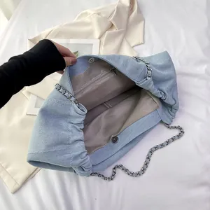 Large denim tote bag with silver chains showing interior zip pocket and magnetic closure