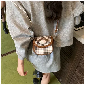 Detailed view of mini crossbody bag with cartoon girl patch and brown checkered pattern