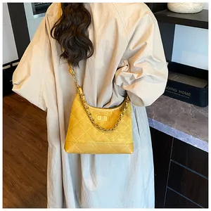 Gros plan du sac bandoulière matelassé jaune avec chaîne dorée et fermoir carré