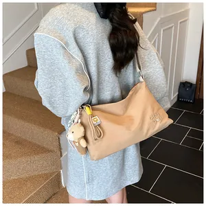 Gros plan du sac bandoulière marron clair avec broderie CHUU DON et porte-clé ours