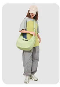 Lichtgroene nylon crossbodytas met grote capaciteit getoond op een model