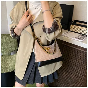 Détail du daim beige matelassé et base en cuir noir sur un sac à bandoulière