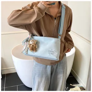 Détail du sac messager bleu clair en nylon avec broderie et un joli pendentif d'ours