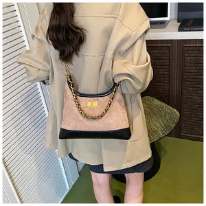 Détail du sac bandoulière en daim beige matelassé avec chaîne dorée et fermoir rotatif