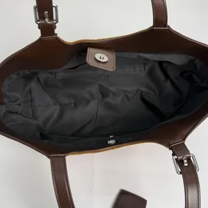 Overhead view of a brown leather tote bag with magnetic closure and black interior lining