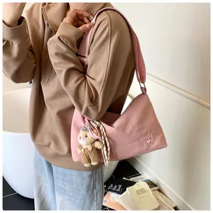 Détail du sac messager rose avec bandoulière réglable et breloque ours en peluche