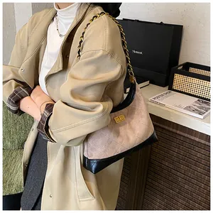 Détail d'un sac à chaîne matelassé rose et noir assorti à un trench et un magazine