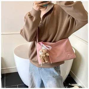 Détail du sac messager en toile rose avec pendentif ours en peluche et broderie