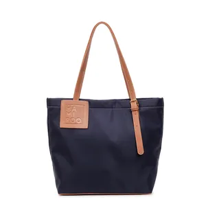 Minimalistische marineblauwe nylon draagtas met bruine lederen handgrepen en logo