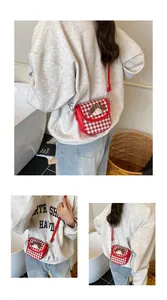 Detail view of red gingham crossbody bag with cute plush character and leather strap