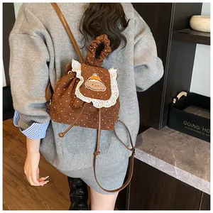 Détail d'un sac à dos en velours côtelé marron avec broderie chien et dentelle