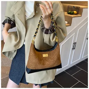 Détail d'un sac bandoulière vintage en daim marron avec chaîne dorée et fermoir en métal