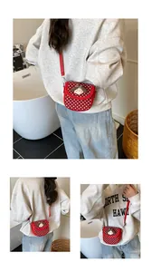 Detail of red polka dot crossbody bag with 3D cartoon character and adjustable strap